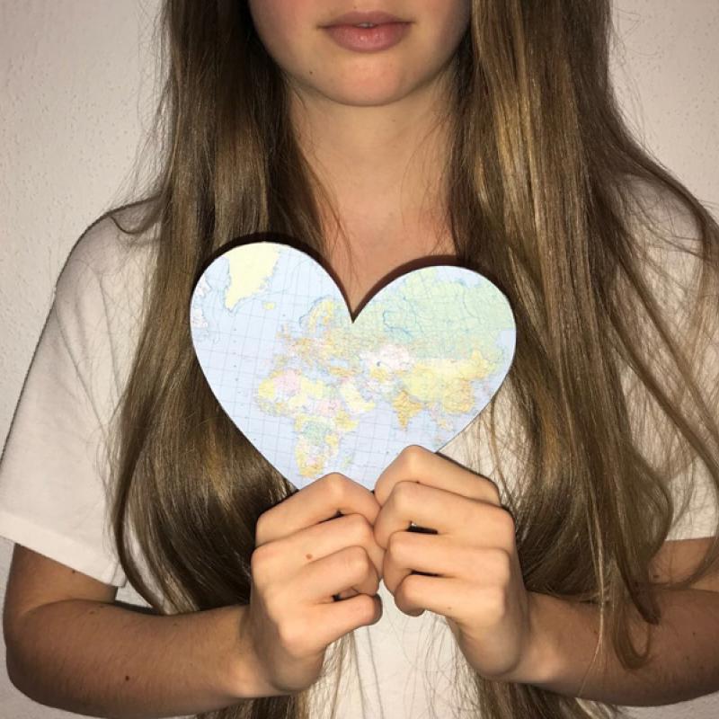 Mädchen mit ausgeschnittenem Herz aus einer Landkarte