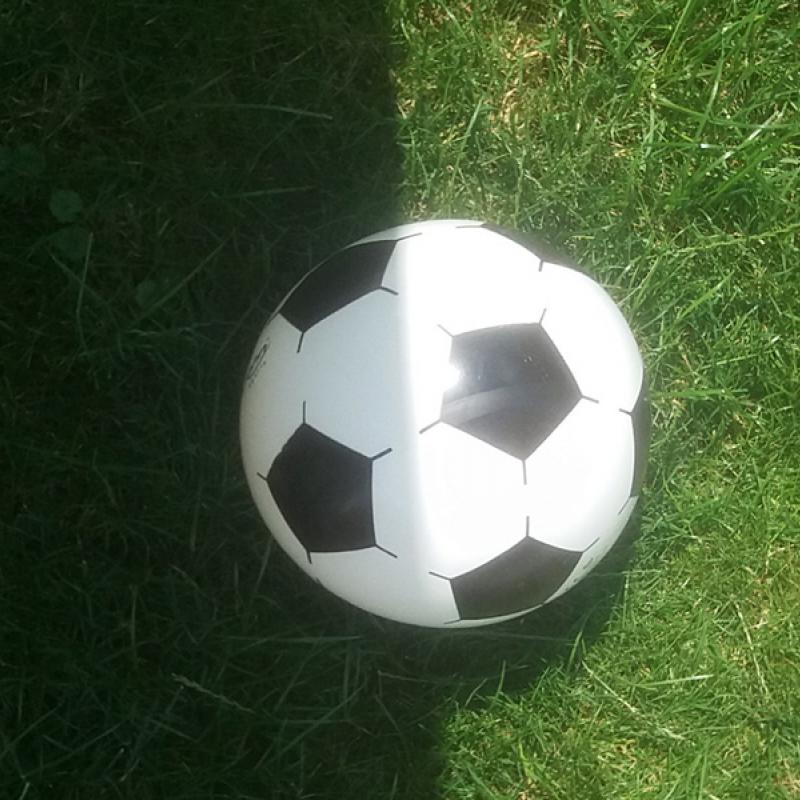 Fußball auf einer Wiese - die halbe Seite im Schatten