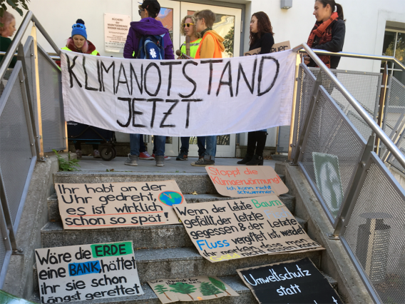Transparent "Klimanotstand", dahinter ein paar Jugendliche und viele andere Schilder