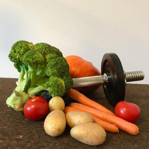 Hantel liegt mit Gemüse auf einem Tisch