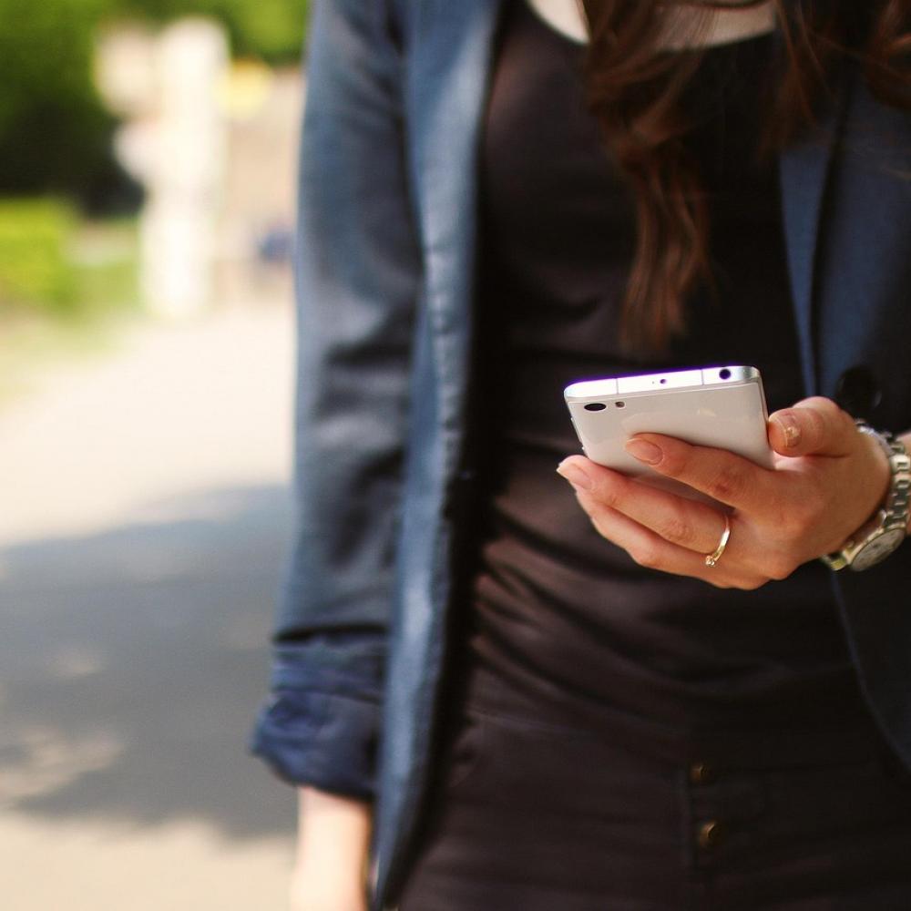 Eine junge Frau hält ein Smartphone in der Hand