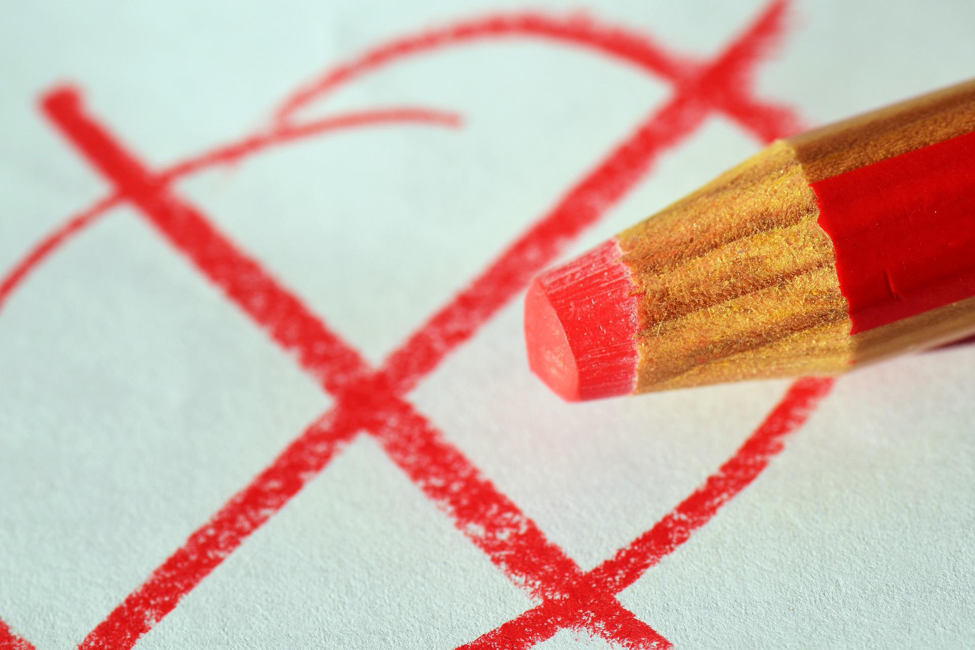 Ein roter Bleistift macht ein rotes Kreuz auf einem Wahlzettel