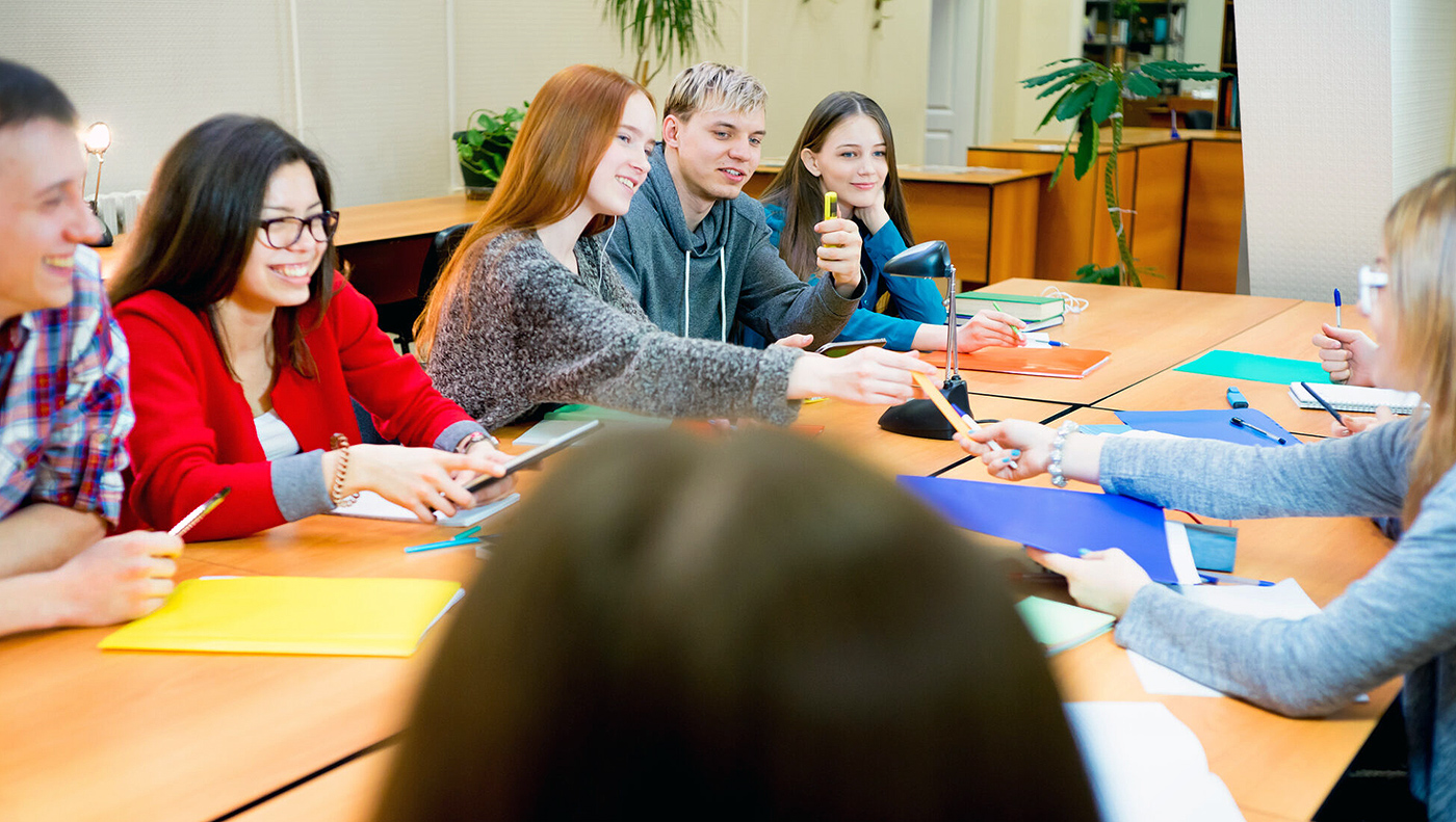 Mehrere junge Menschen sitzen an einem Tischen und entscheiden gemeinsam über wichtige Themen.