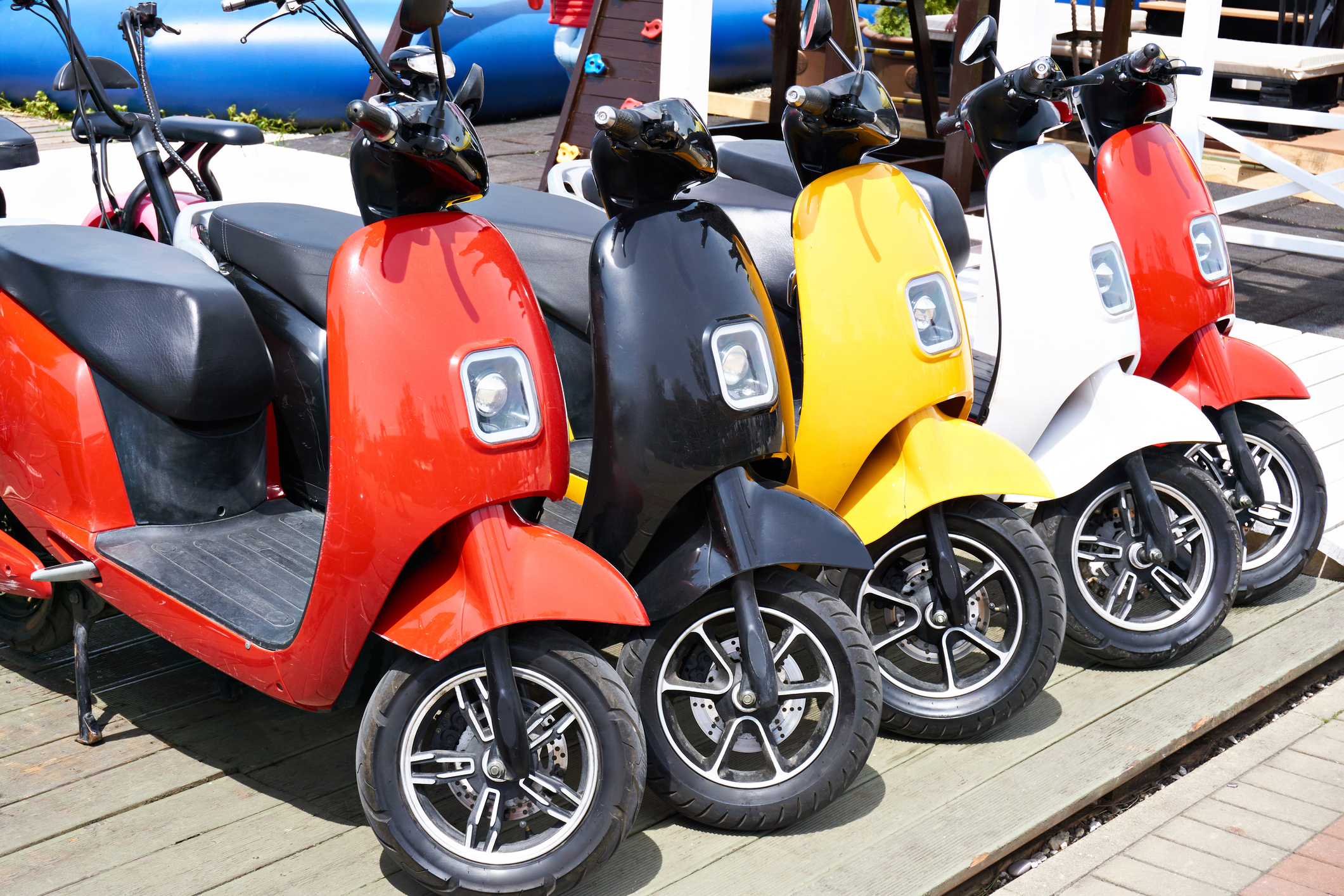 Eine Reihe mit vier parkenden E-Mopeds in bunten Farben.